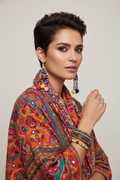 Woman with pixie hair wearing rainbow pom-pom earrings